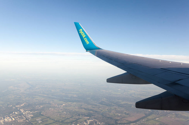 The wings of the airplane Ukrainian International Airlines are above the clear sky at sunset - Foto, Imagem