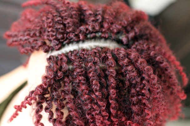 Αφρικανική μαλλιά σγουρά χτένισμα με τεχνητά μαλλιά, οδηγός διαδικασία εργασίας, κόκκινα μαλλιά κοντινό, μπούκλες, λευκό φόντο, Αφρικανικά μαλλιά, κλιπ μαλλιών, καθοδήγηση, επέκταση τρίχας - Φωτογραφία, εικόνα