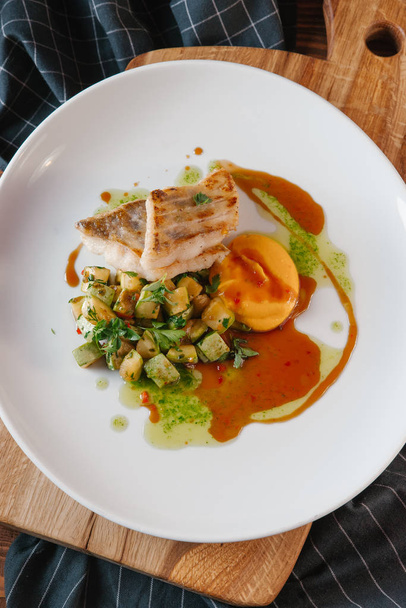 Kızarmış balık parçaları ile squash ve soslar ahşap tahta üzerinde beyaz tabakta servis - Fotoğraf, Görsel