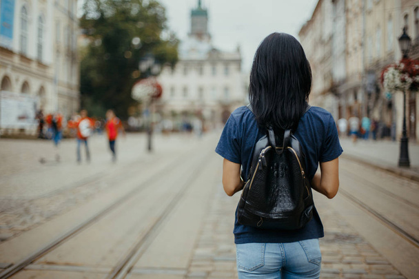 Молодая туристка с кожаным рюкзаком, гуляющая по старому городу Львова. Пространство для текста
 - Фото, изображение