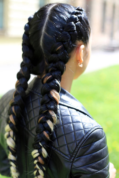 two braids, a fashionable hairstyle of the girl, braided by the master hairdresser, the result of work close-up against the background of nature - Photo, Image