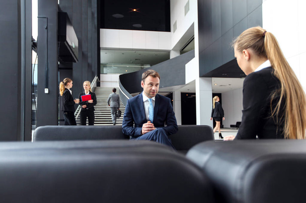 Business people talking sitting on sofa at office lobby, break, interview concept - Фото, изображение