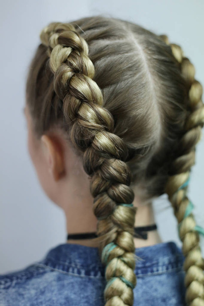 zwei dicke Zöpfe mit einem Kanekalon auf hellem Haar, eine Jugendfrisur - Foto, Bild