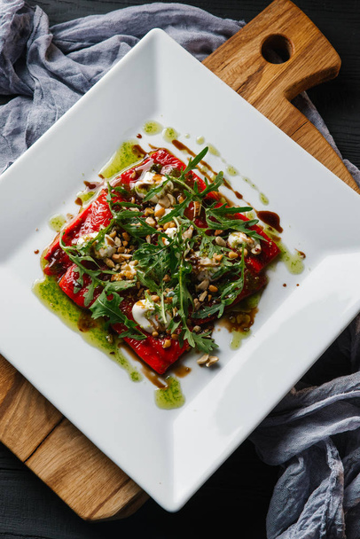 Овощной салат с перцем на гриле, свежей рукколой и орехами на белой тарелке
 - Фото, изображение