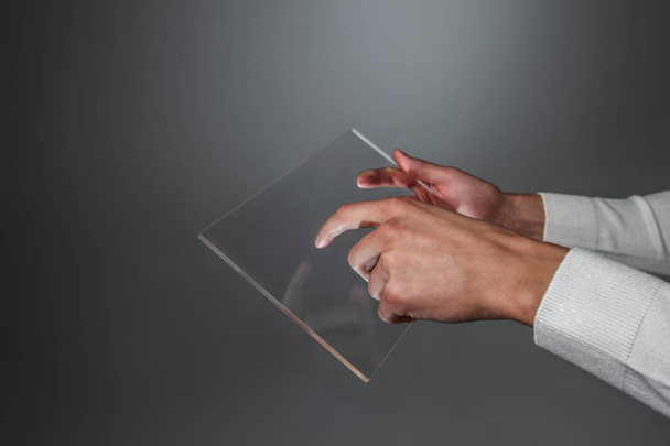 Male hands holding blank futuristic transparent digital tablet pc computer with copy space - 写真・画像