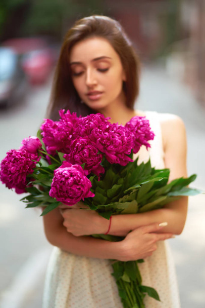 Spring / Summer Style. Beautiful Young Brunette Woman In A Nice Spring Dress With A Bouquet Of Pions. Beautiful Spring Street. Fashion Spring Summer Photo. - 写真・画像