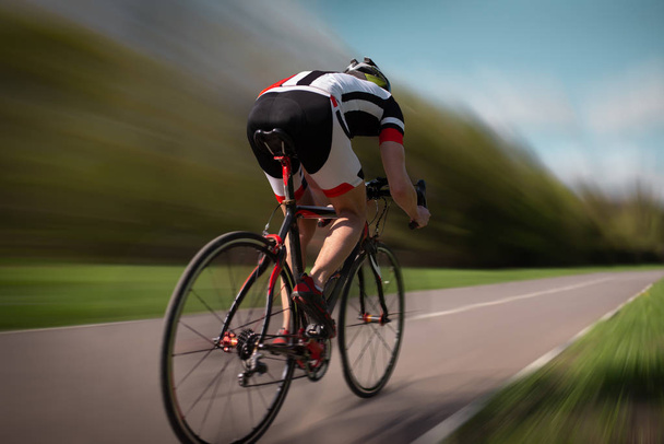 ciclista di sesso maschile in casco e abbigliamento sportivo in bicicletta, vista posteriore
  - Foto, immagini