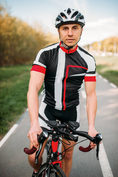 Ciclista in casco e abbigliamento sportivo durante l'allenamento in bicicletta. Allenamento su pista ciclabile, ciclismo
 - Foto, immagini