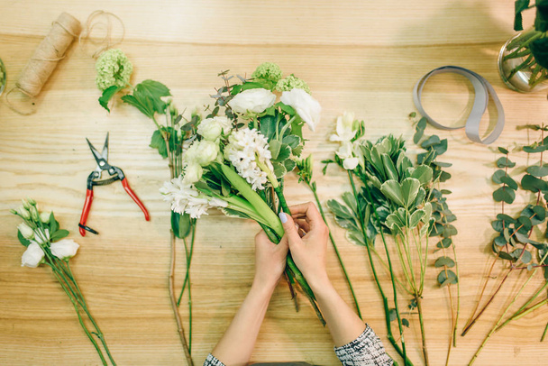 mani di fiorista femminile facendo composizione floreale con fiori bianchi
  - Foto, immagini