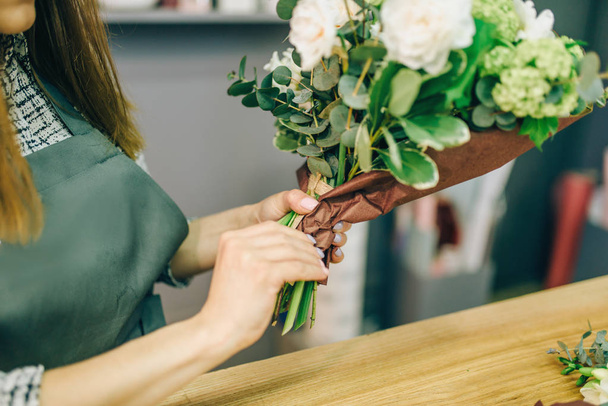 Женщина-флористка, украшающая композицию из свежих цветов. Цветочный бизнес
 - Фото, изображение