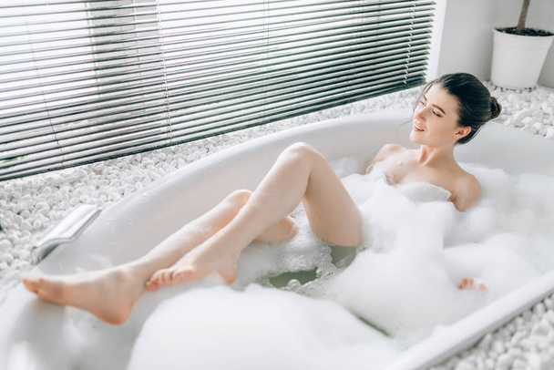 atrakcyjna kobieta, leżąc w kąpieli z pianką i pokazuje nogi, relaks, zdrowie i Pielęgnacja skóry koncepcja - Zdjęcie, obraz
