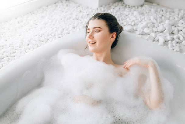 attraktive Frau im Bad liegend mit Schaumstoff, Entspannungs-, Gesundheits- und Pflegekonzept - Foto, Bild