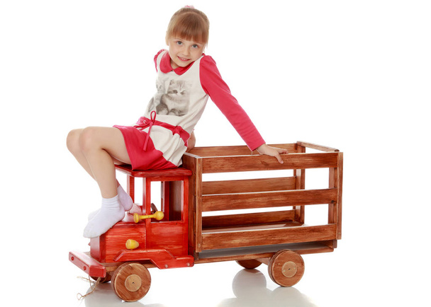 Little girl is playing with a wooden car. - Φωτογραφία, εικόνα