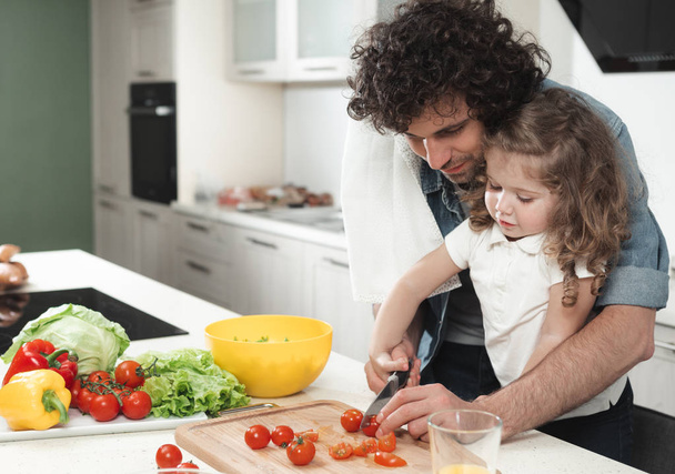 Cheerful father and daughter making salad in kitchen  - Фото, изображение