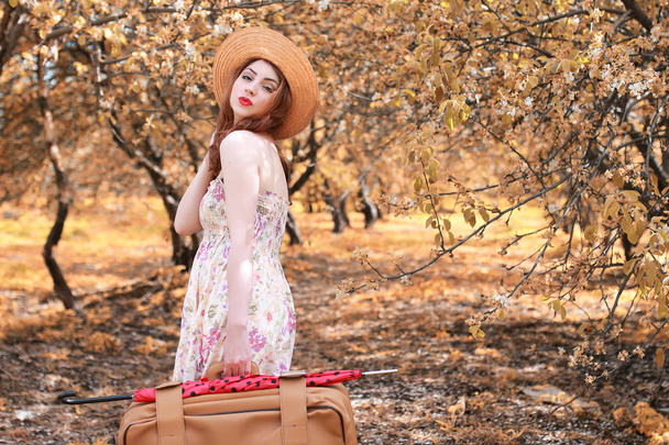 niña con maleta de cuero para viajar en el parque de otoño a pie
 - Foto, imagen