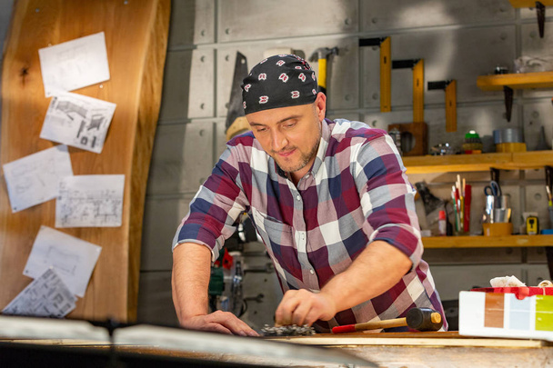 Carpintero haciendo su trabajo en el taller de carpintería. un hombre en un taller de carpintería mide y corta laminado
 - Foto, imagen