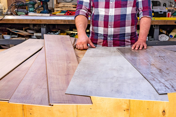 Carpintero haciendo su trabajo en el taller de carpintería. un hombre en un taller de carpintería mide y corta laminado
 - Foto, Imagen