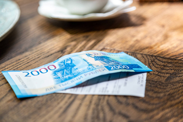 neue russische Banknoten im Wert von 2000 Rubel in männlicher Hand, er wird die Rechnung in einem Restaurant bezahlen - Foto, Bild