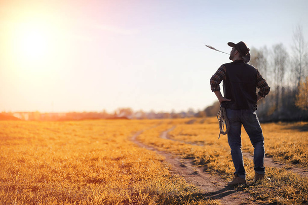 A man cowboy hat and a loso in the field. American farmer in a f - Zdjęcie, obraz