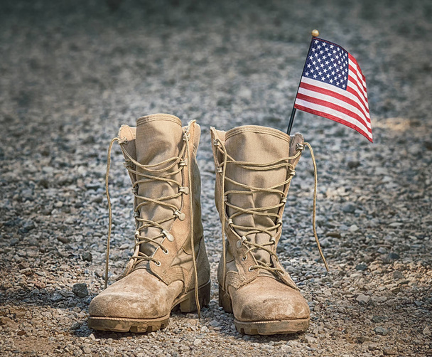 Old military combat boots with the American flag. Rocky gravel background. Memorial Day or Veterans day concept.  - Zdjęcie, obraz