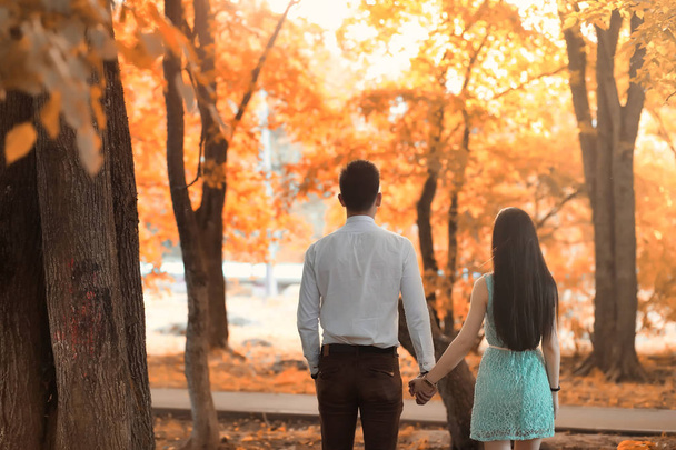 秋の公園で歩く若いカップルします。  - 写真・画像