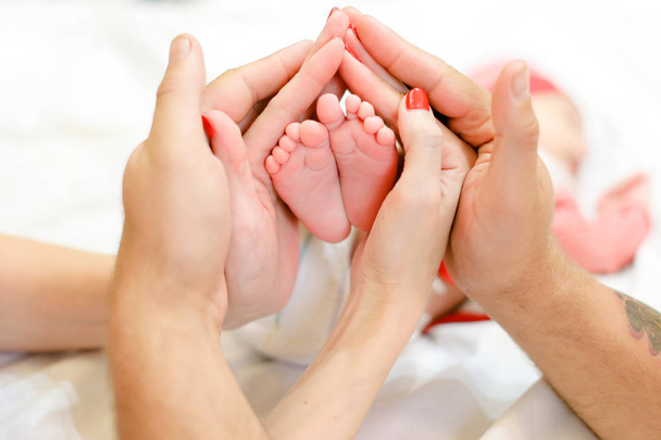 Οι γονείς τα χέρια κρατώντας τα πόδια νεογέννητο μωρό. - Φωτογραφία, εικόνα