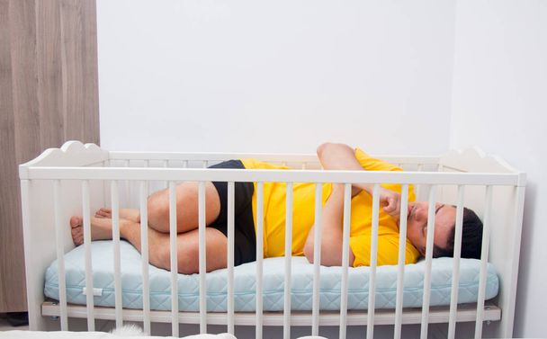 väsynyt isä nukkuu lastensängyssä
 - Valokuva, kuva