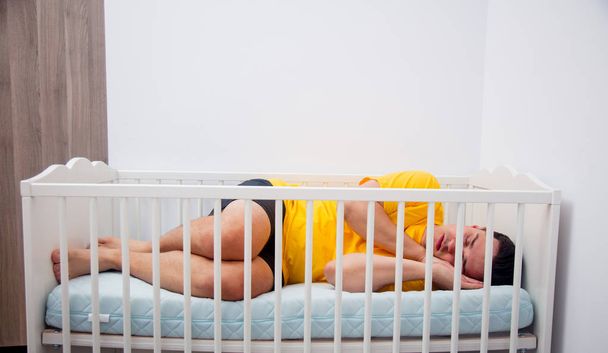 père fatigué dormir dans un lit d'enfant
 - Photo, image