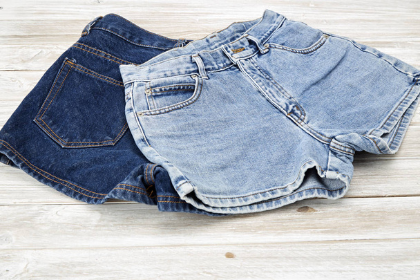 two vintage woman Jeans denim shorts on wooden shelf. shorts from new collection - Фото, изображение
