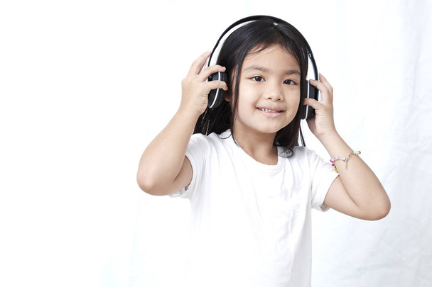 Nettes kleines Mädchen mit Smartphone und Kopfhörer, das Musik hört und tanzt - Foto, Bild