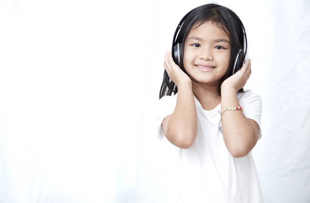 Nettes kleines Mädchen mit Smartphone und Kopfhörer, das Musik hört und tanzt - Foto, Bild