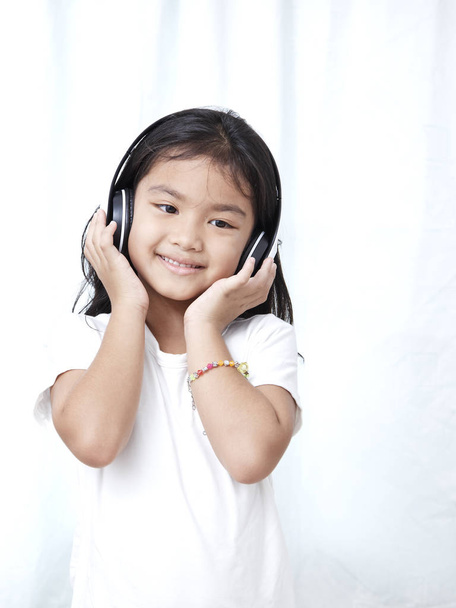 Ładna dziewczynka ze smartfonem i słuchawki słuchać muzyki i tańca - Zdjęcie, obraz