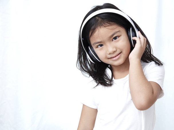 Cute little girl with smartphone and headphones listening to music and dancing - Fotoğraf, Görsel