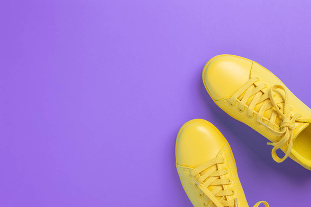 Pair of yellow shoes on violet background. - Photo, Image