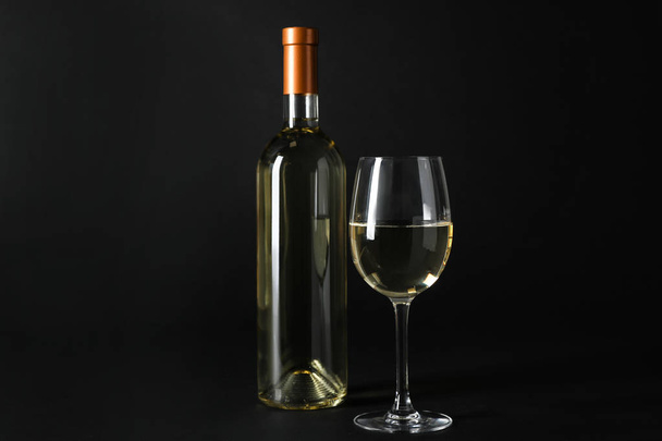 Bottle and glass of expensive white wine on dark background - 写真・画像