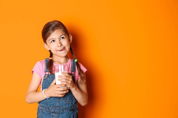 Cute little girl with glass of milk on color background - Фото, зображення