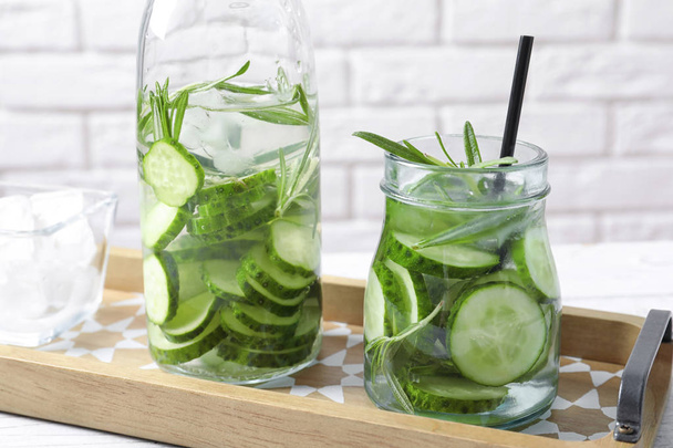 Natural lemonade with cucumber and rosemary in glassware on table - Fotó, kép