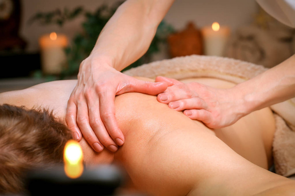 Jonge man ontvangende schouder en terug massage van therapeut in spa - Foto, afbeelding