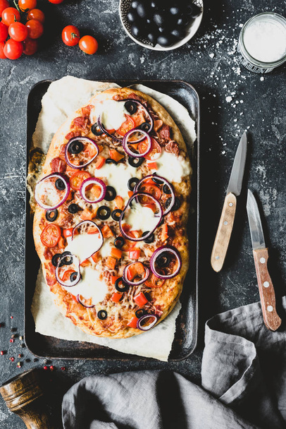 Flatbread pizza with mozzarella and black olives on wooden pizza board, top view - 写真・画像