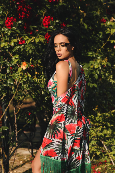 fashion outdoor photo of beautiful woman with dark hair in elegant beach clothes posing in summer garden - 写真・画像
