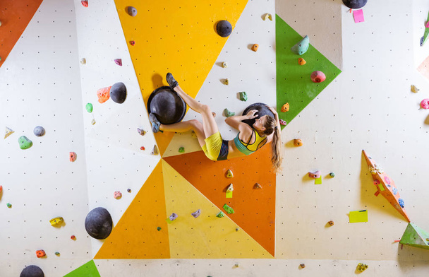 Joven mujer bouldering desafiante ruta en interior escalada gimnasio
 - Foto, Imagen