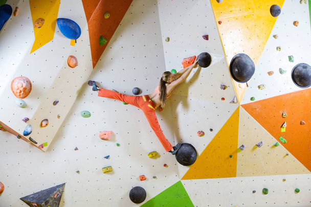 Young woman climbing challenging bouldering route. In indoor climbing gym. - Photo, Image