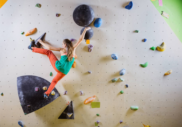 Genç kadın tırmanma bouldering rota. Tırmanma kapalı spor salonunda. - Fotoğraf, Görsel