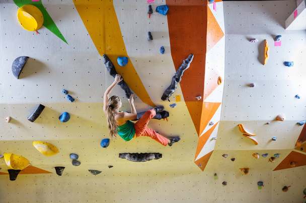 Jonge vrouw boulderen in indoor klimmen sportschool - Foto, afbeelding