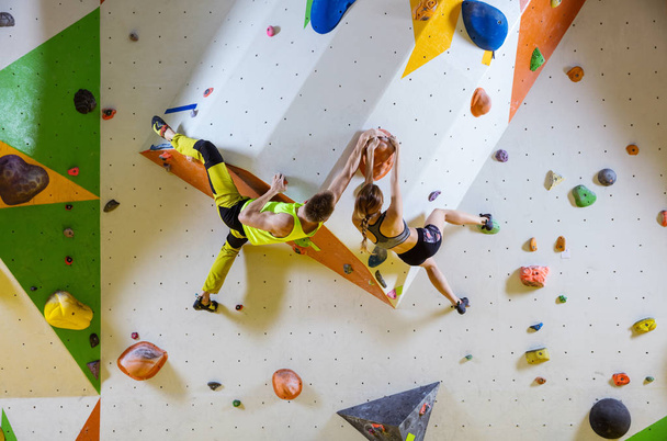 Kletterer in einer Kletterhalle. junges Paar klettert Boulderprobleme (Routen), ergreift denselben Griff. - Foto, Bild