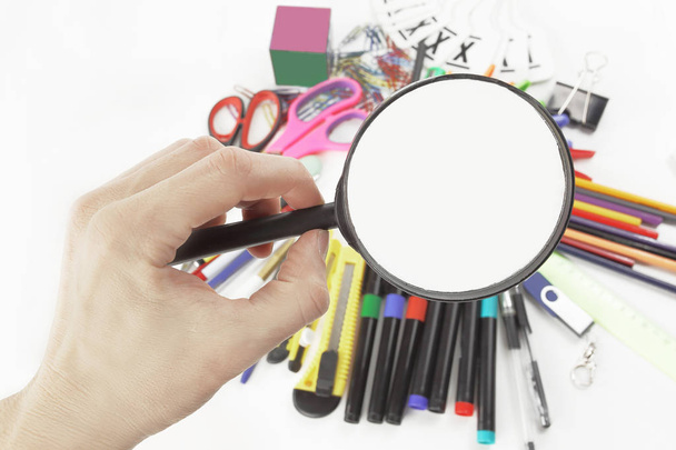 hand with magnifying glass over school supplies .photo with copy space. - Photo, Image