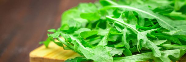 Fresh juicy leaves of arugula on a brown wooden table. - Foto, immagini