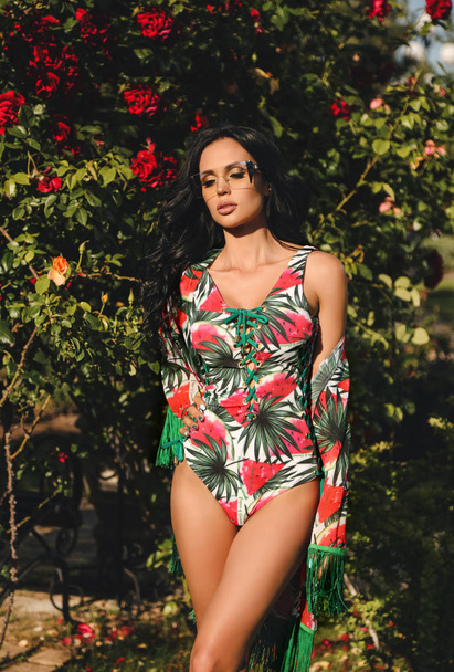 fashion outdoor photo of beautiful woman with dark hair in elegant beach clothes posing in summer garden - 写真・画像