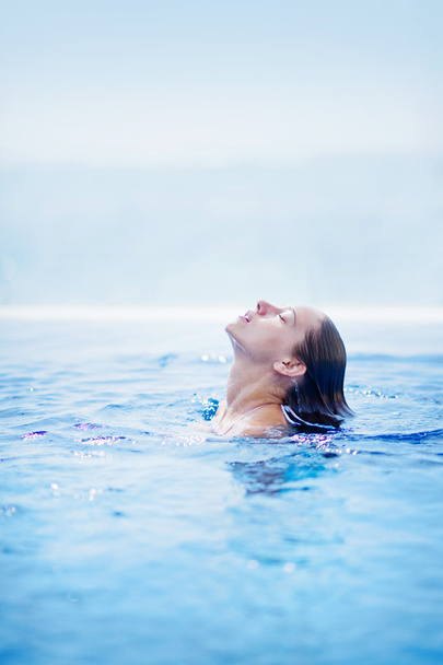 Young beautiful woman dives in swimming pool in Bali - Foto, Imagen