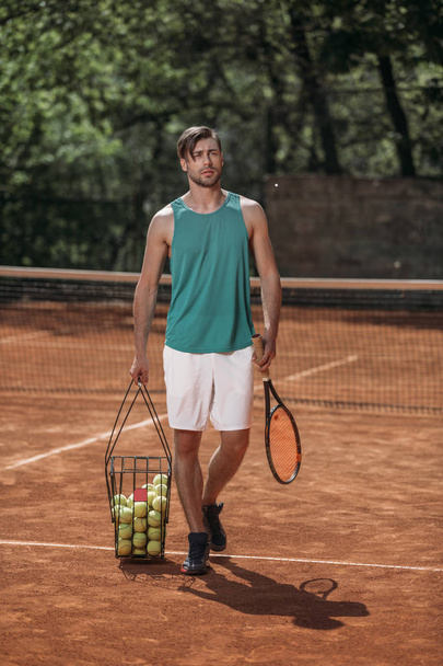 joueur de tennis portant panier de balles sur le court
 - Photo, image